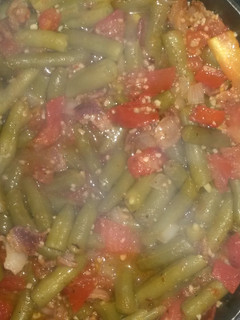 A picture of Green beans with tomato and bacon.