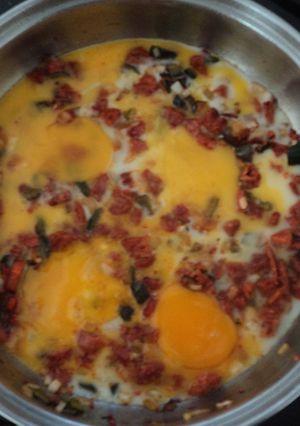 Una foto de Huevos rancheros de tocino, chorizo, jamón y chiles de agua