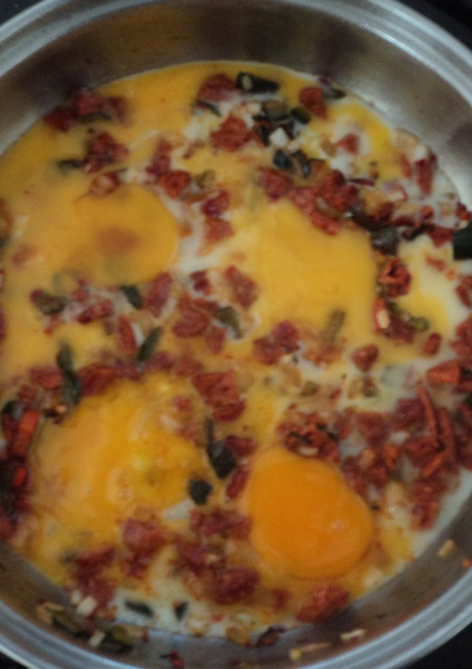 Una foto de Huevos rancheros de tocino, chorizo, jamón y chiles de agua