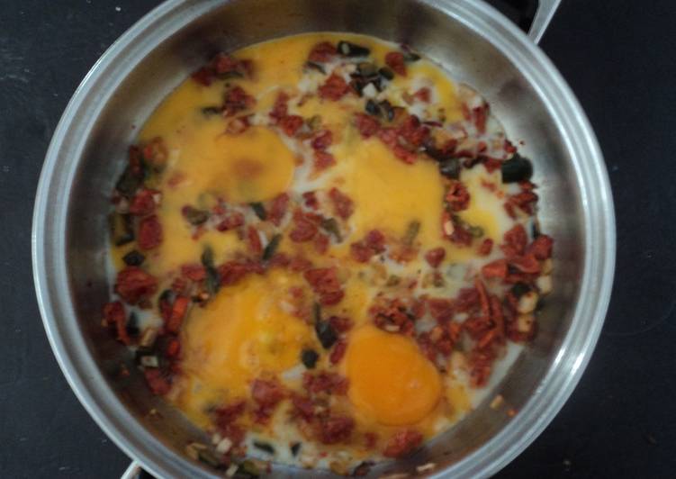 Huevos rancheros de tocino, chorizo, jamón y chiles de agua