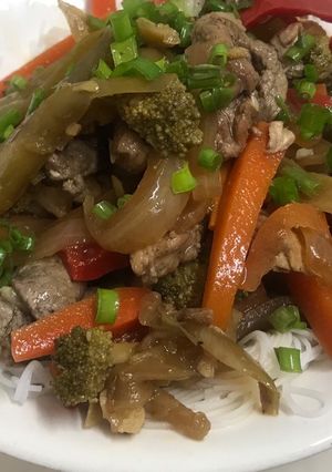 Una foto de Vegetales con pollo y cerdo al Wok sobre fideos de arroz