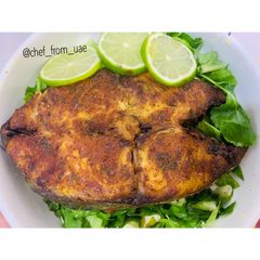A picture of Baked Tilapia Fish served with rocket leaves.