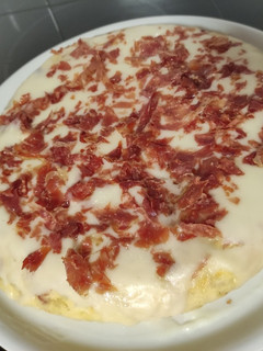 Una foto de Tortilla de patatas rellena de jamón serrano y topping de alioli y jamón crujiente