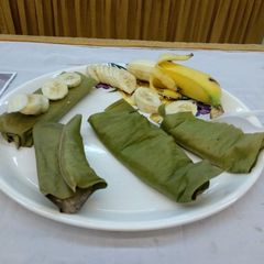 A picture of Steamed banana cake wrapped in banana leaves.