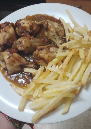 Una foto de Jamoncitos de pollo adobados y asados en freidora de aire con salsa de Cola-Cola y papas fritas