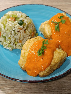 Una foto de Bacalao rebozado con salsa de piquillo y guarnición de arroz con verduras