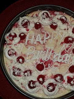A picture of White chocolate raspberry swirl cheesecake topped with raspberries and sauce.