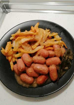 Una foto de Salchichas al vino acompañado de patatas fritas