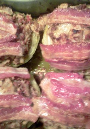 A picture of Stuffed baked cabbage heads topped w bacon.