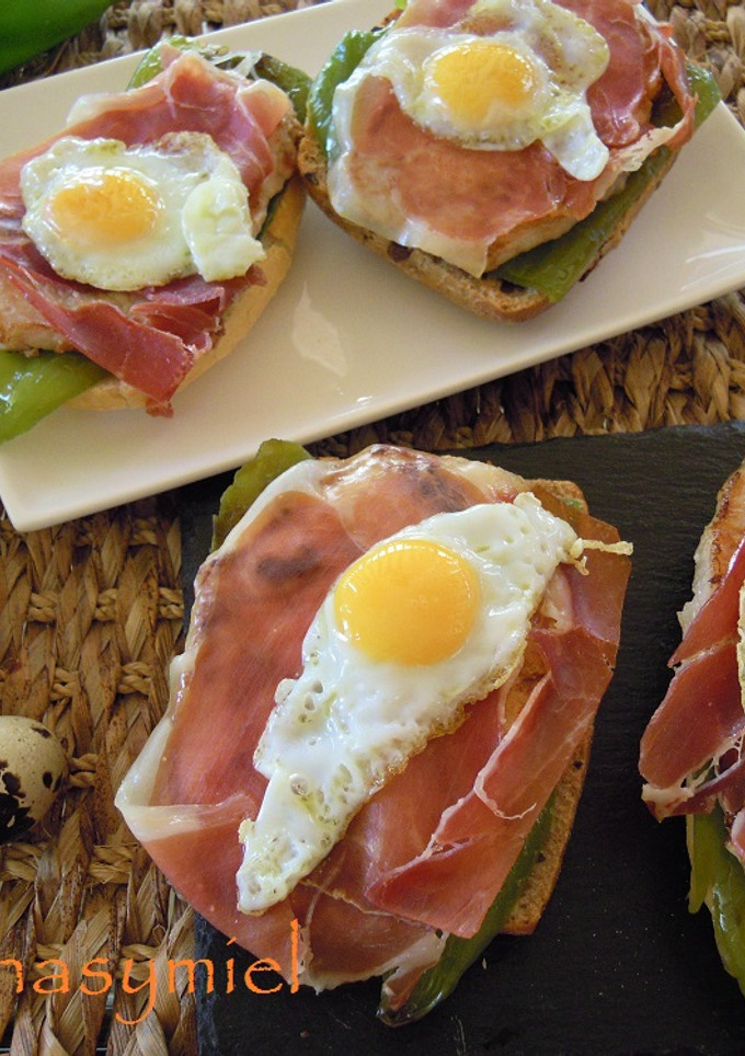 Una foto de Tosta de lomo, pimiento, jamón y huevo de codorniz
