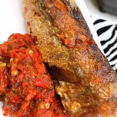 A picture of Roasted pepper sauce and fried hake fish.