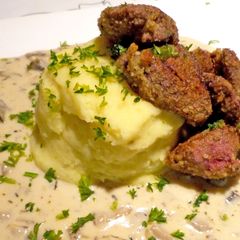 A picture of Chicken livers with mushroom sauce on garlic hash.