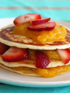 A picture of Yogurt pancakes with cinnamon mango coulis and strawberries.