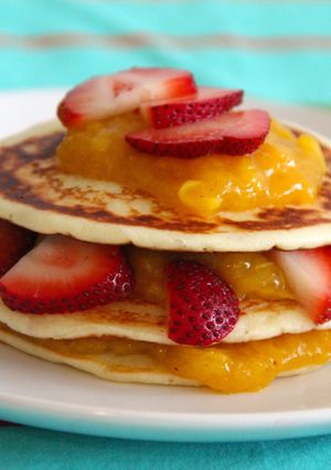 A picture of Yogurt pancakes with cinnamon mango coulis and strawberries.