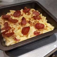 A picture of Mac n Cheese topped with crispy salami.