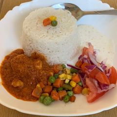 A picture of Garlic rice with gravy chicken and veggies and salad raita.