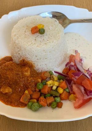 A picture of Garlic rice with gravy chicken and veggies and salad raita.