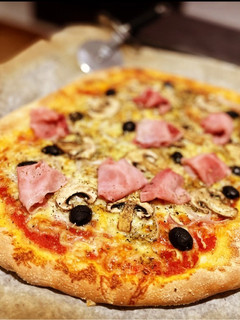 Una foto de Pizza casera: prosciutto e fungi con olivas negras