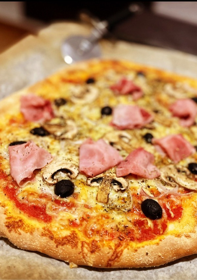 Una foto de Pizza casera: prosciutto e fungi con olivas negras