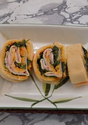 Una foto de Pionono con mayonesa de zanahorias relleno con rúcula, jamón y queso