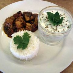 A picture of Achar (eastern pickle) Chicken curry served with rice and a mint and cucumber raita..