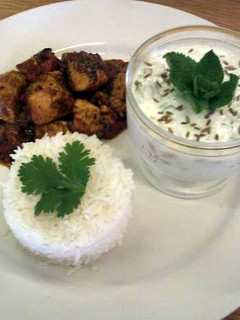 A picture of Achar (eastern pickle) Chicken curry served with rice and a mint and cucumber raita..
