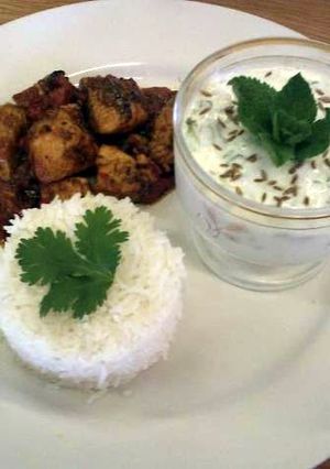 A picture of Achar (eastern pickle) Chicken curry served with rice and a mint and cucumber raita..