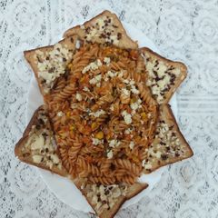 A picture of Red sauce chicken pasta with garlic bread.