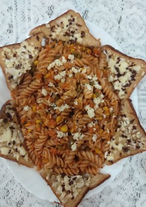 A picture of Red sauce chicken pasta with garlic bread.