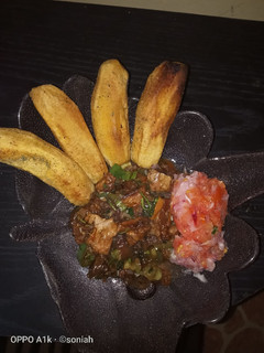 A picture of Fried plantains,with beef stew and a side of kachumbari(salsa).