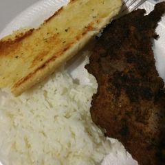 A picture of Fried steak with rice and garlic bread.