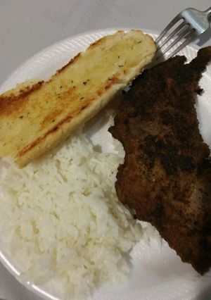 A picture of Fried steak with rice and garlic bread.