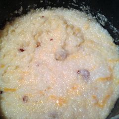 A picture of chessy grits with bacon.