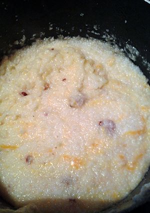 A picture of chessy grits with bacon.