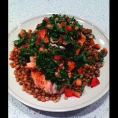 A picture of salmon with anchovies sauce and green lentils.