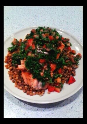 A picture of salmon with anchovies sauce and green lentils.