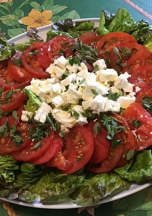 Une photo de Salade de tomates à la laitue rouge, feta et basilic frais sauce balsamique