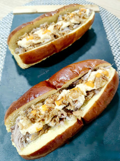 Una foto de Brioche de cerdo a baja temperatura con cebolla crunch y salsa de quesos parmesano y cheddar