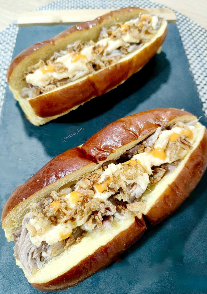 Una foto de Brioche de cerdo a baja temperatura con cebolla crunch y salsa de quesos parmesano y cheddar