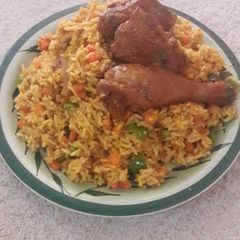 A picture of Jollpf rice with veggies and fried chicken.