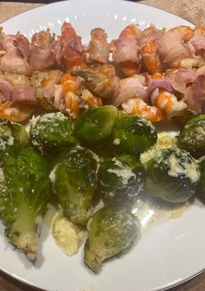Una foto de Brochetes de langostinos y panceta ahumada con repollitos de brusellas gratinados con parmesano