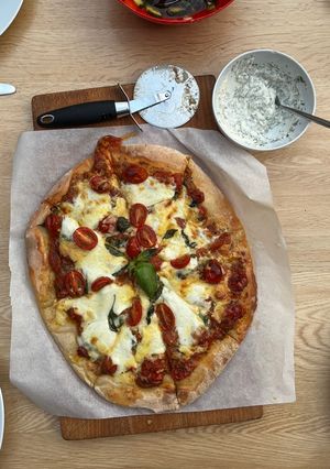 A picture of Caprese pizza with garlic and herb dip.