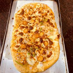 A picture of Pizza with chicken chunks toppings.