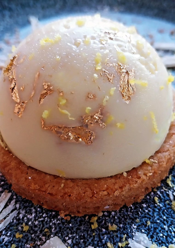 Una foto de Mousse de limón con polvo de oro y cobertura de chocolate blanco