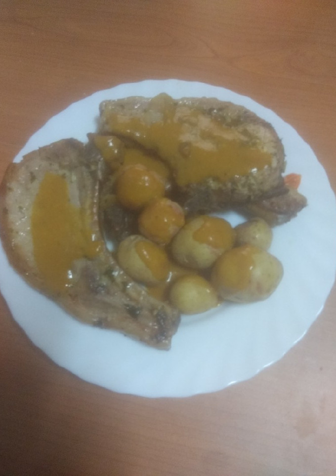 Una foto de Chuletas de cerdo adobadas con papas arrugás y salsa