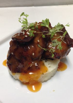 A picture of crispy pig cheeks with spicy pineapple,orange glaze and thai basil,lemon rice.
