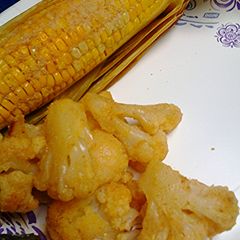 A picture of Oven roasted corn unhusked and cauliflower.
