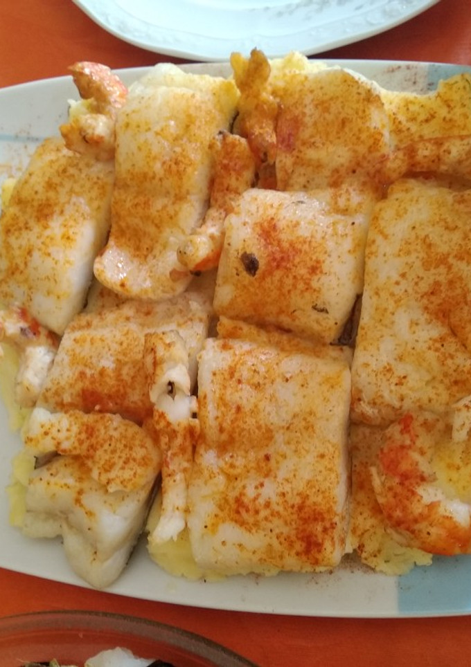 Una foto de Bacalao al vapor con langostinos y cama de patatas