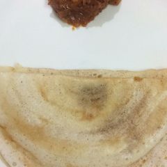 A picture of Dosa and tomato chutney.