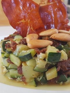 Una foto de Timbal de calabacín con tomates secos y crujiente de jamón